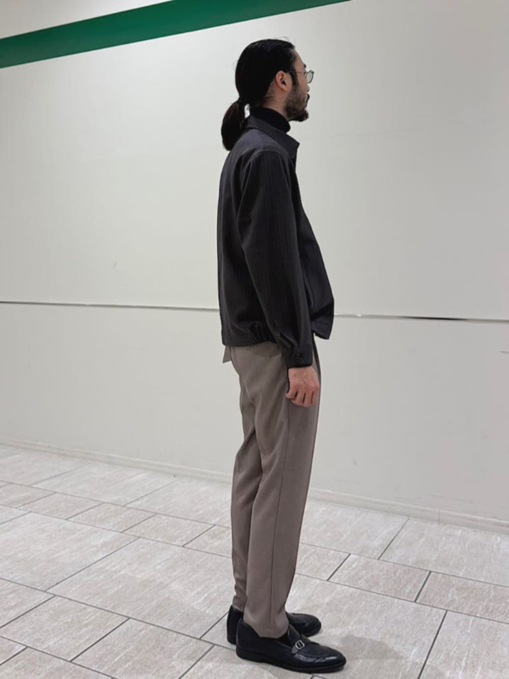 ベージュ系のスラックス、グレー系のニット/セーター、グレー系のブルゾンを着用したメンズの冬コーディネートの2枚目の写真