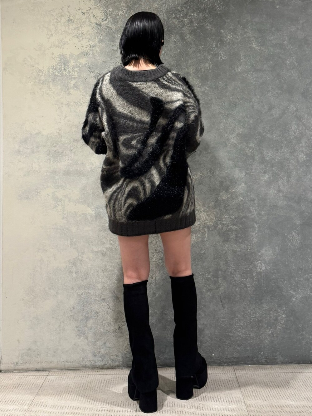 グレー系のニット/セーター、ブラック系のスカート、ブラック系のブーツを着用したレディースの秋コーディネートの3枚目の写真