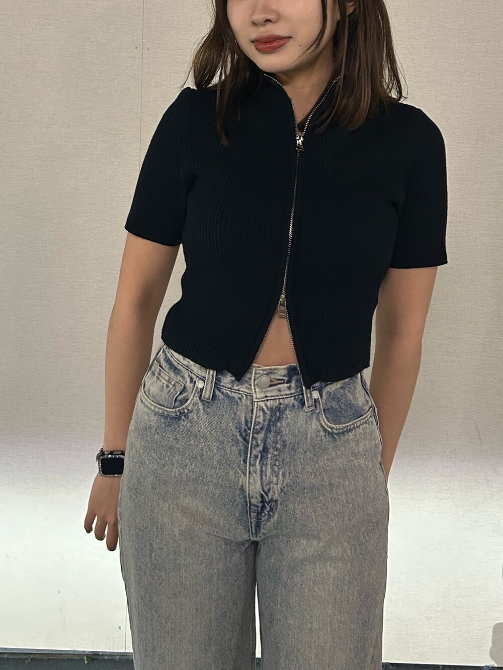 ブラック系のニット/セーター、ブルー系のデニムパンツ、ブラック系のスニーカーを着用したレディースの春コーディネートの5枚目の写真