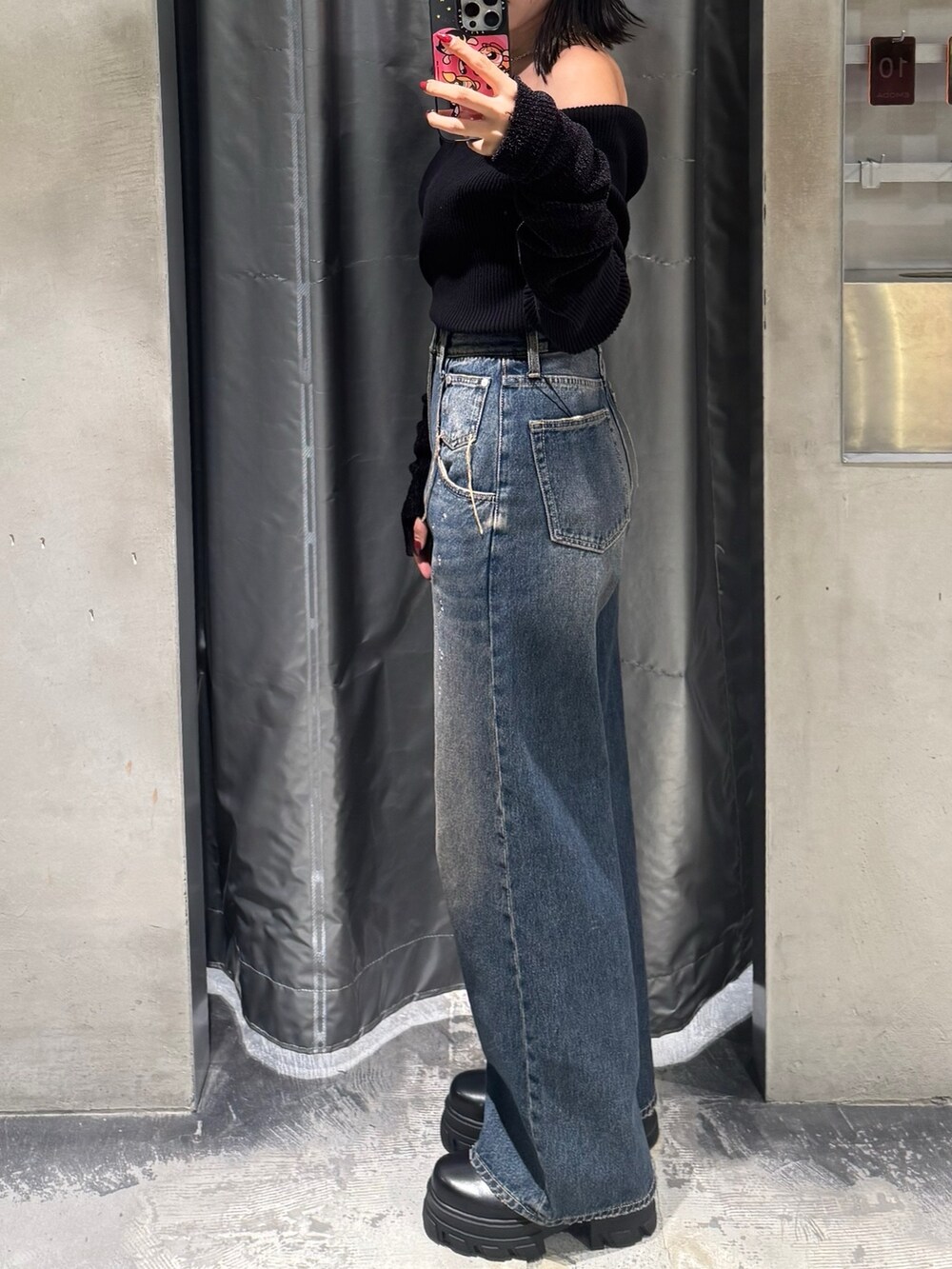 ブラック系のニット/セーター、ブルー系のデニムパンツ、ブラック系のブーツを着用したレディースの秋コーディネートの2枚目の写真