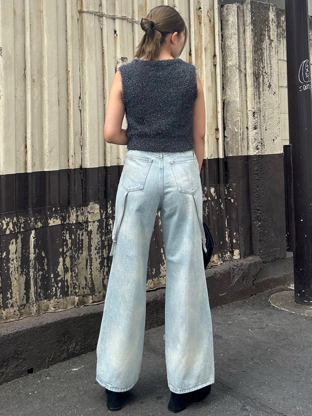 グレー系のタンクトップ、ブルー系のデニムパンツ、ブラック系のサンダルを着用したレディースの夏コーディネートの2枚目の写真