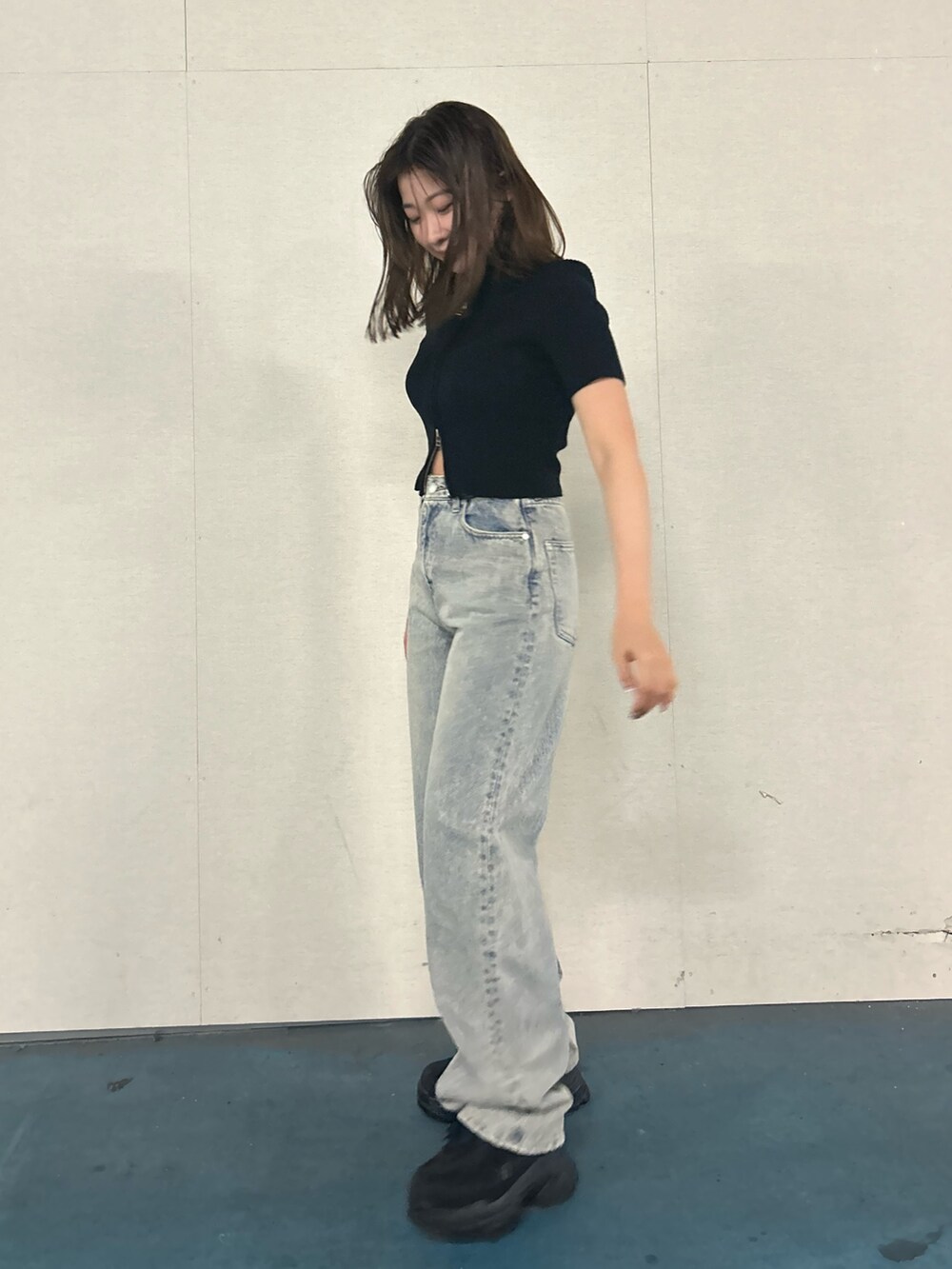 ブラック系のニット/セーター、ブルー系のデニムパンツ、ブラック系のスニーカーを着用したレディースの春コーディネートの2枚目の写真