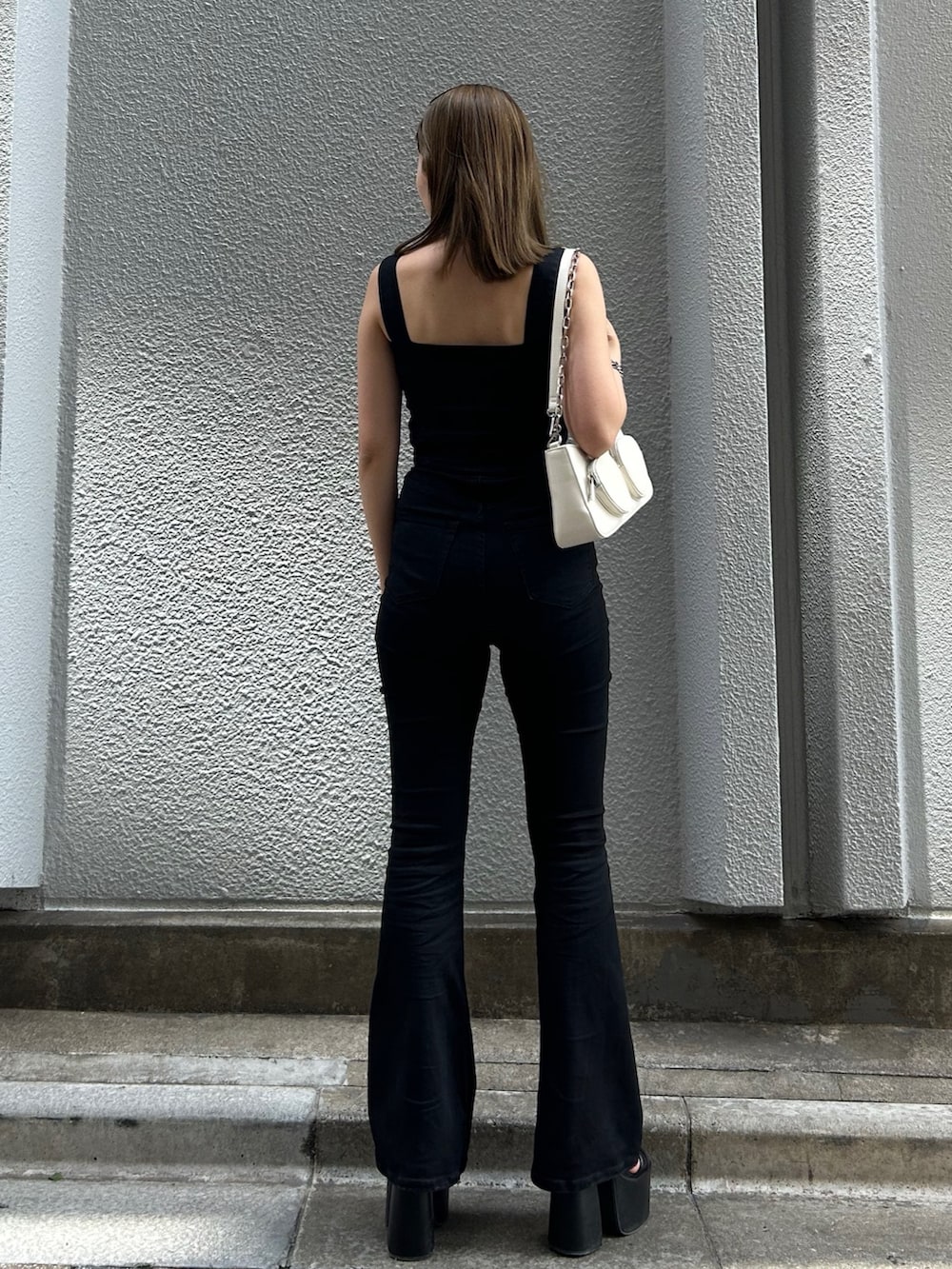 ブラック系のサロペット/オーバーオール、ブラック系のサンダル、ホワイト系のショルダーバッグを着用したレディースの春コーディネートの4枚目の写真