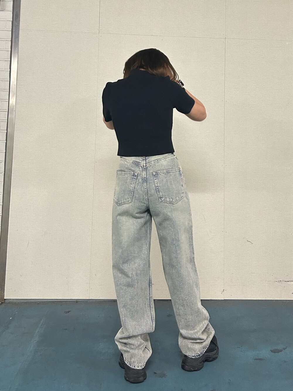 ブラック系のニット/セーター、ブルー系のデニムパンツ、ブラック系のスニーカーを着用したレディースの春コーディネートの3枚目の写真