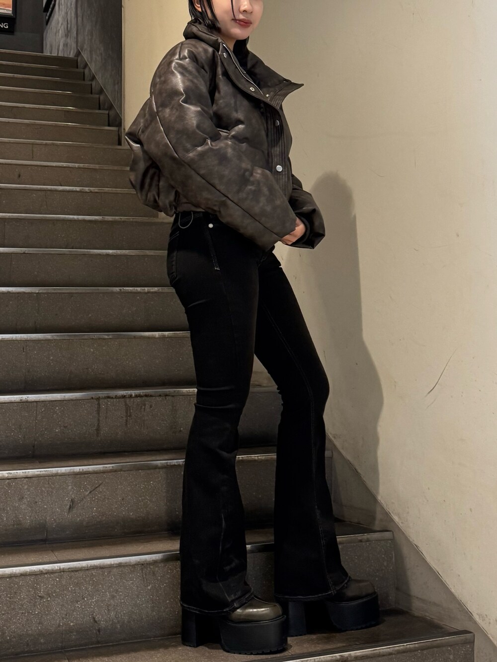 ブラウン系のダウンジャケット/コート、ブラック系のニット/セーター、ブラック系のデニムパンツを着用したレディースの冬コーディネートの2枚目の写真