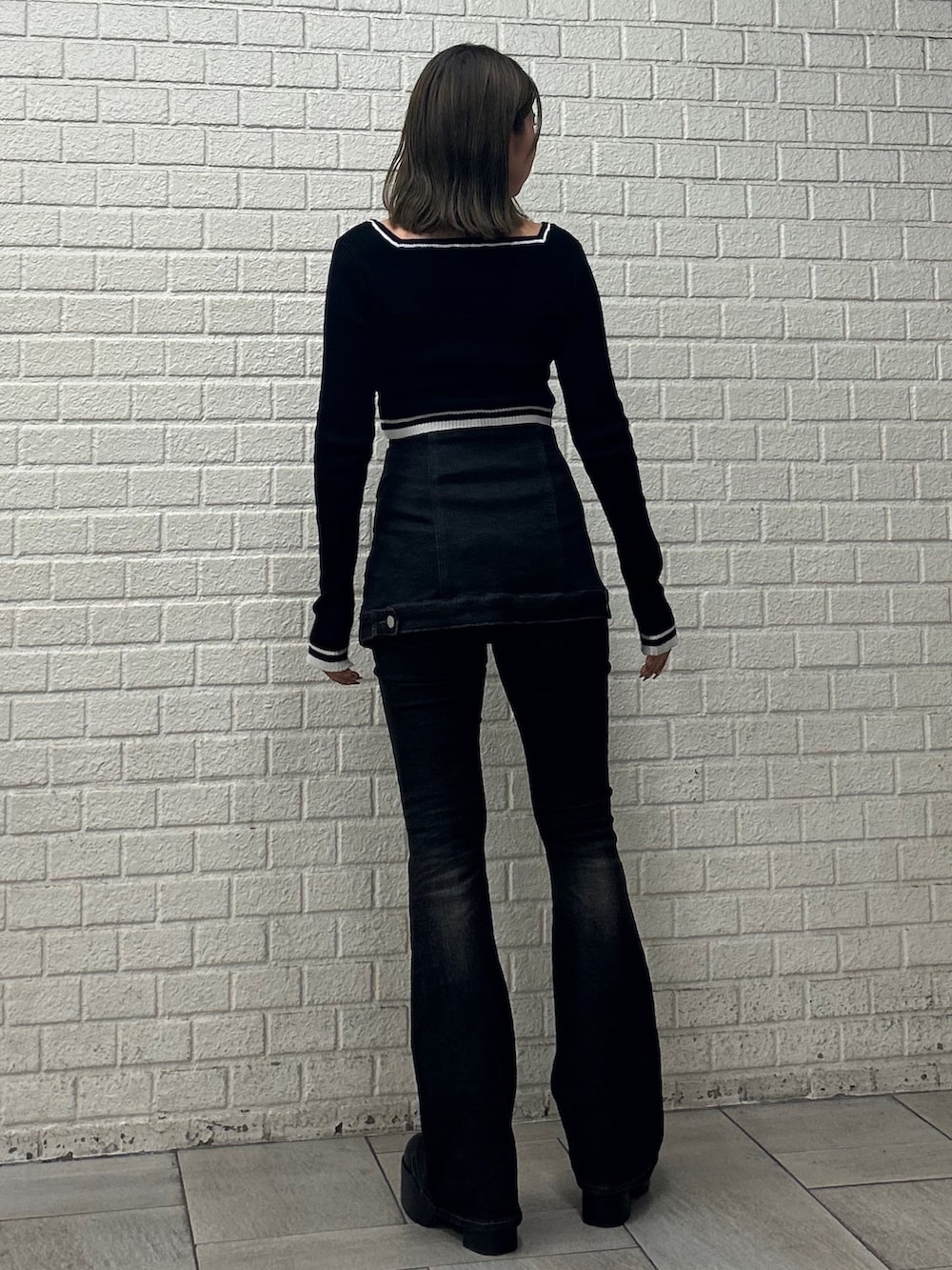 ブラック系のニット/セーター、ブラック系のデニムパンツ、ブラック系のブーツを着用したレディースの秋コーディネートの2枚目の写真