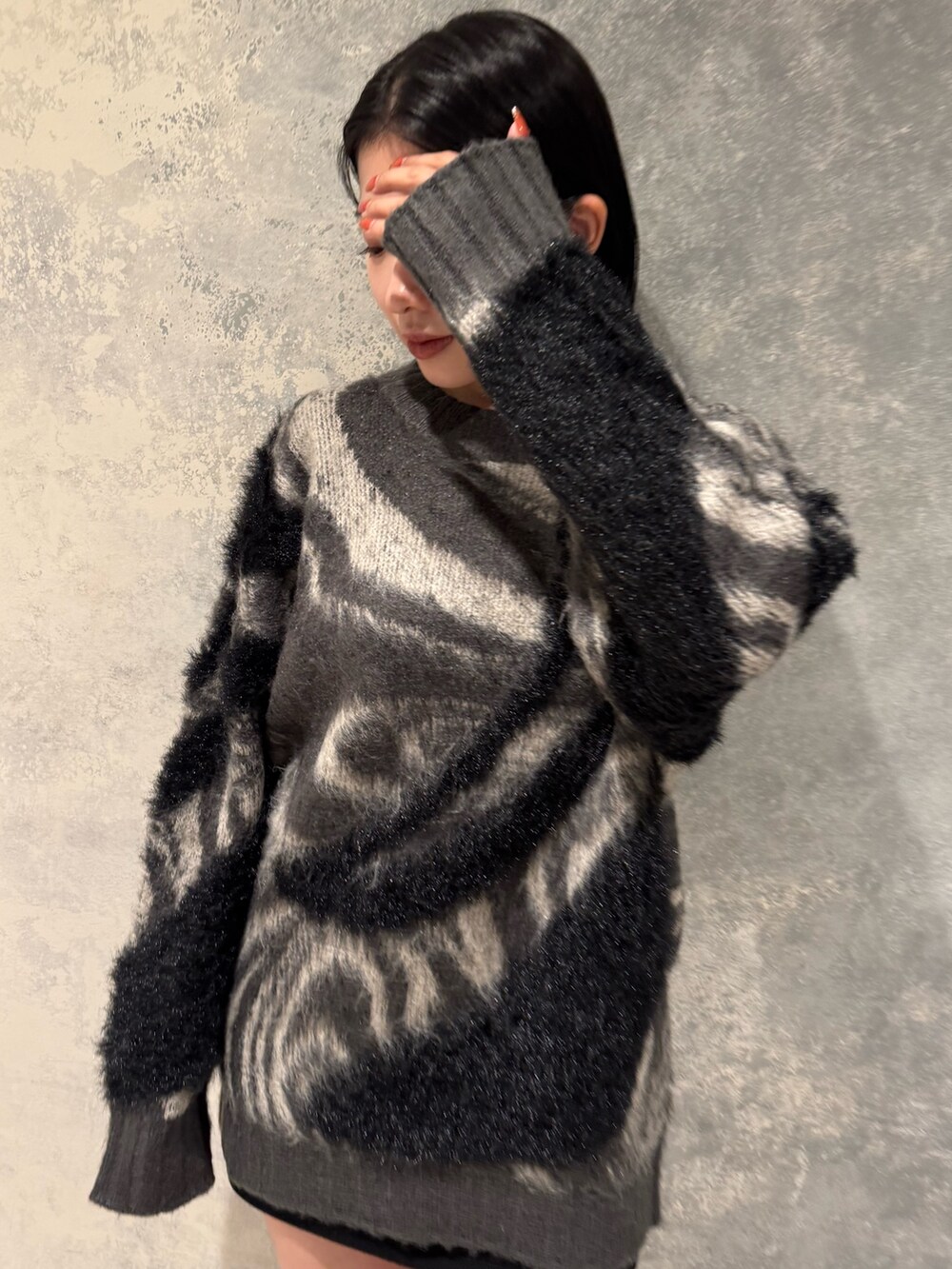 グレー系のニット/セーター、ブラック系のスカート、ブラック系のブーツを着用したレディースの秋コーディネートの2枚目の写真