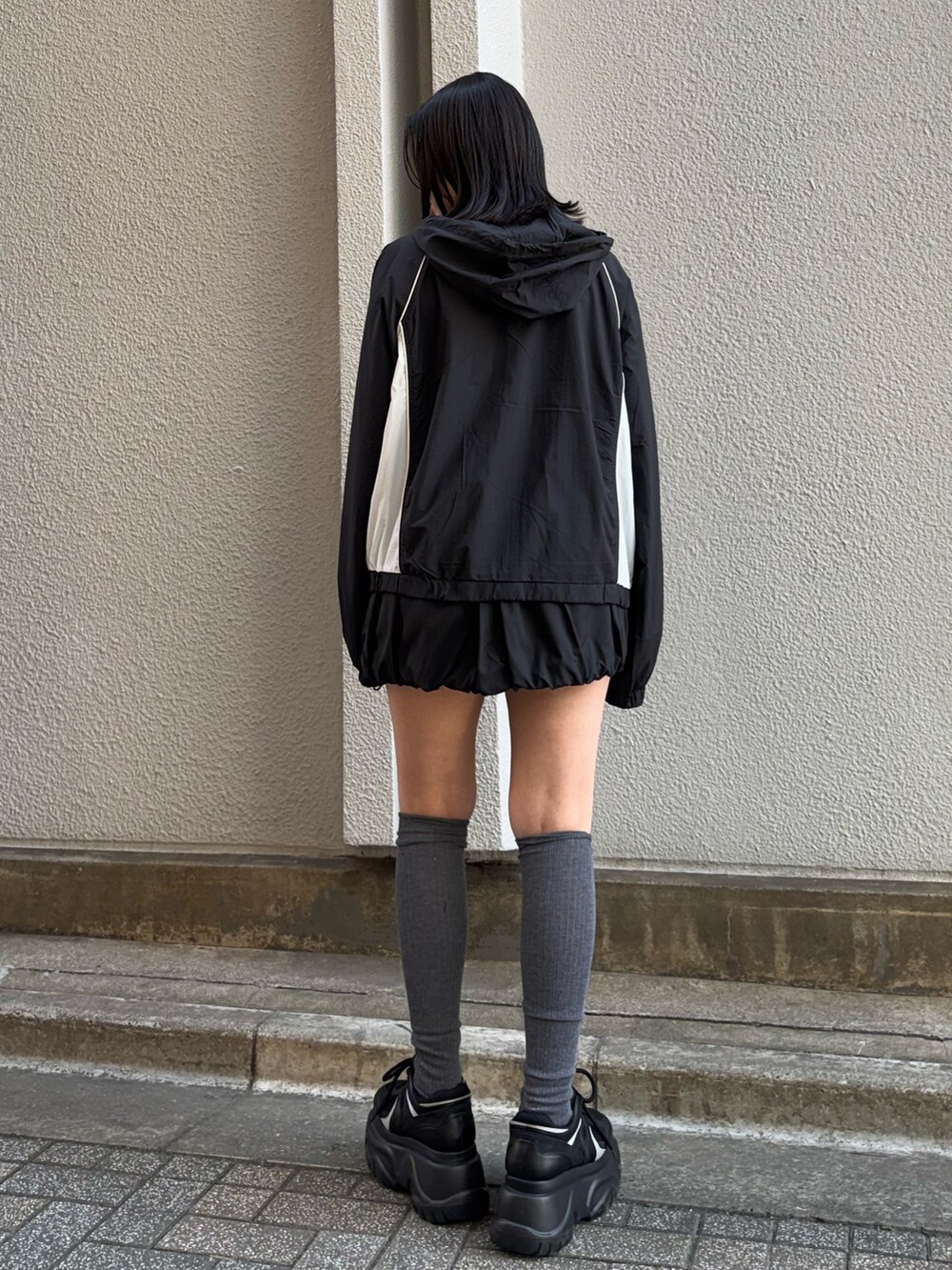 ブラック系のブルゾン、ブラック系のスカート、ブラック系のスニーカーを着用したレディースの冬コーディネートの3枚目の写真