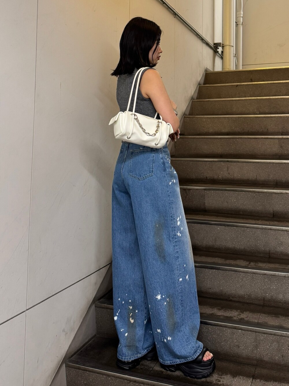 グレー系のニット/セーター、ブルー系のデニムパンツ、ブラック系のサンダルを着用したレディースの夏コーディネートの2枚目の写真