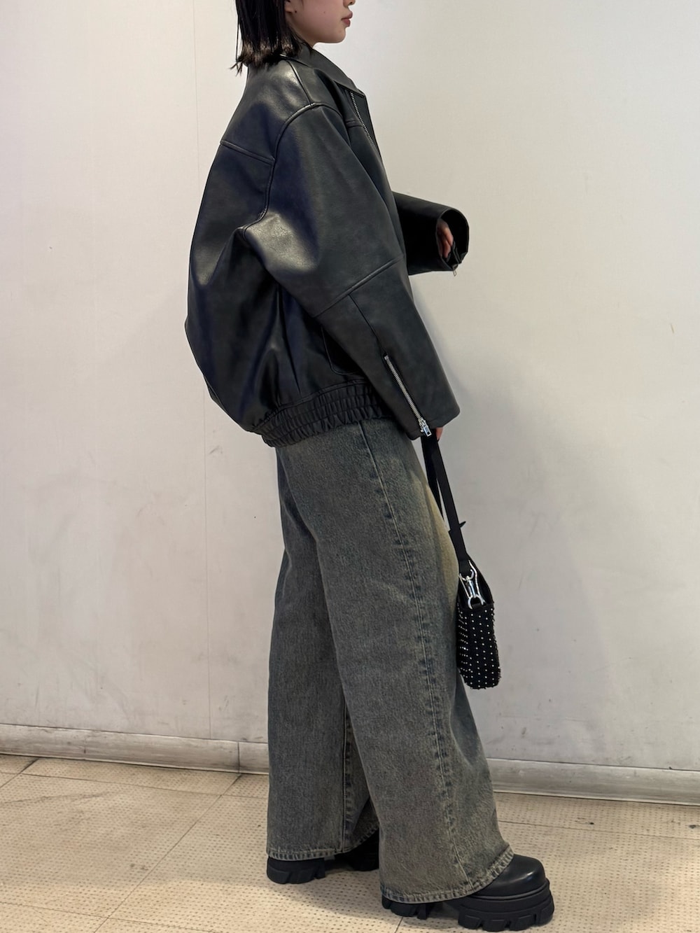 ブラック系のブルゾン、ブラック系のニット/セーター、ブルー系のデニムパンツを着用したレディースの冬コーディネートの2枚目の写真