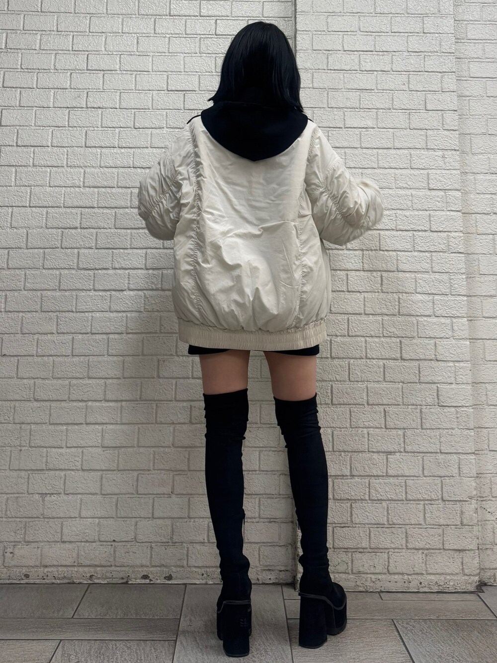 ブラック系のパーカー、ホワイト系のブルゾン、ブラック系のスカートを着用したレディースの秋コーディネートの2枚目の写真