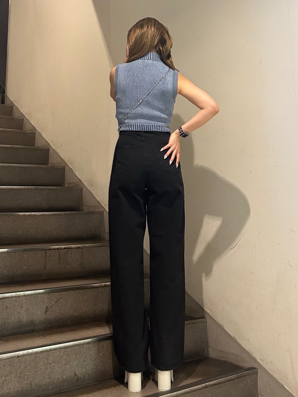 ブルー系のニット/セーター、ブラック系のデニムパンツ、ホワイト系のサンダルを着用したレディースの夏コーディネートの4枚目の写真