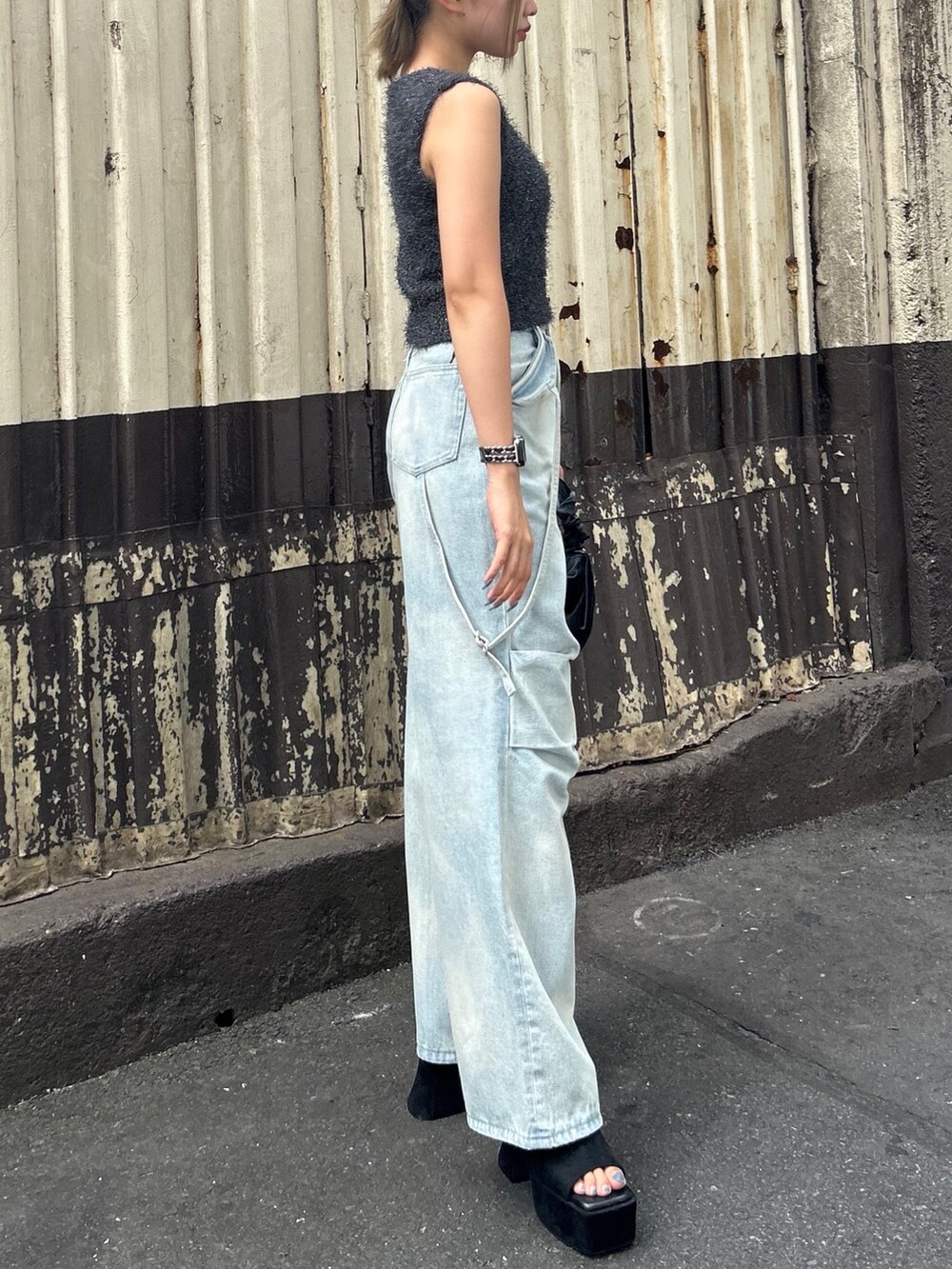 グレー系のタンクトップ、ブルー系のデニムパンツ、ブラック系のサンダルを着用したレディースの夏コーディネートの5枚目の写真