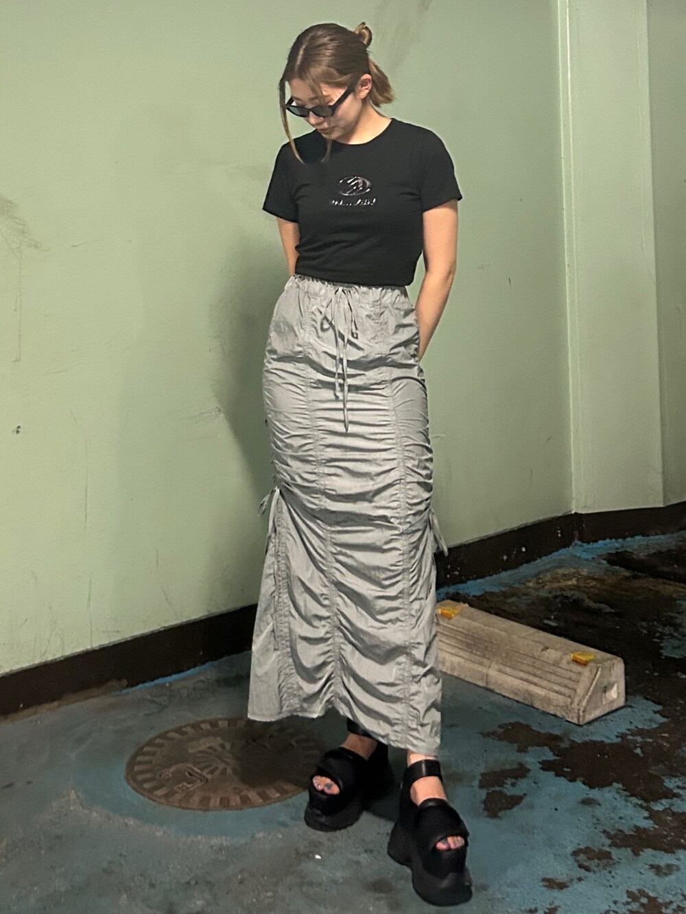 ブラック系のTシャツ/カットソー、グレー系のスカート、ブラック系のサンダルを着用したレディースの夏コーディネートの5枚目の写真