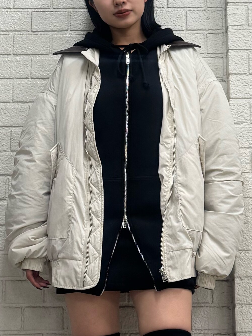 ブラック系のパーカー、ホワイト系のブルゾン、ブラック系のスカートを着用したレディースの秋コーディネートの4枚目の写真