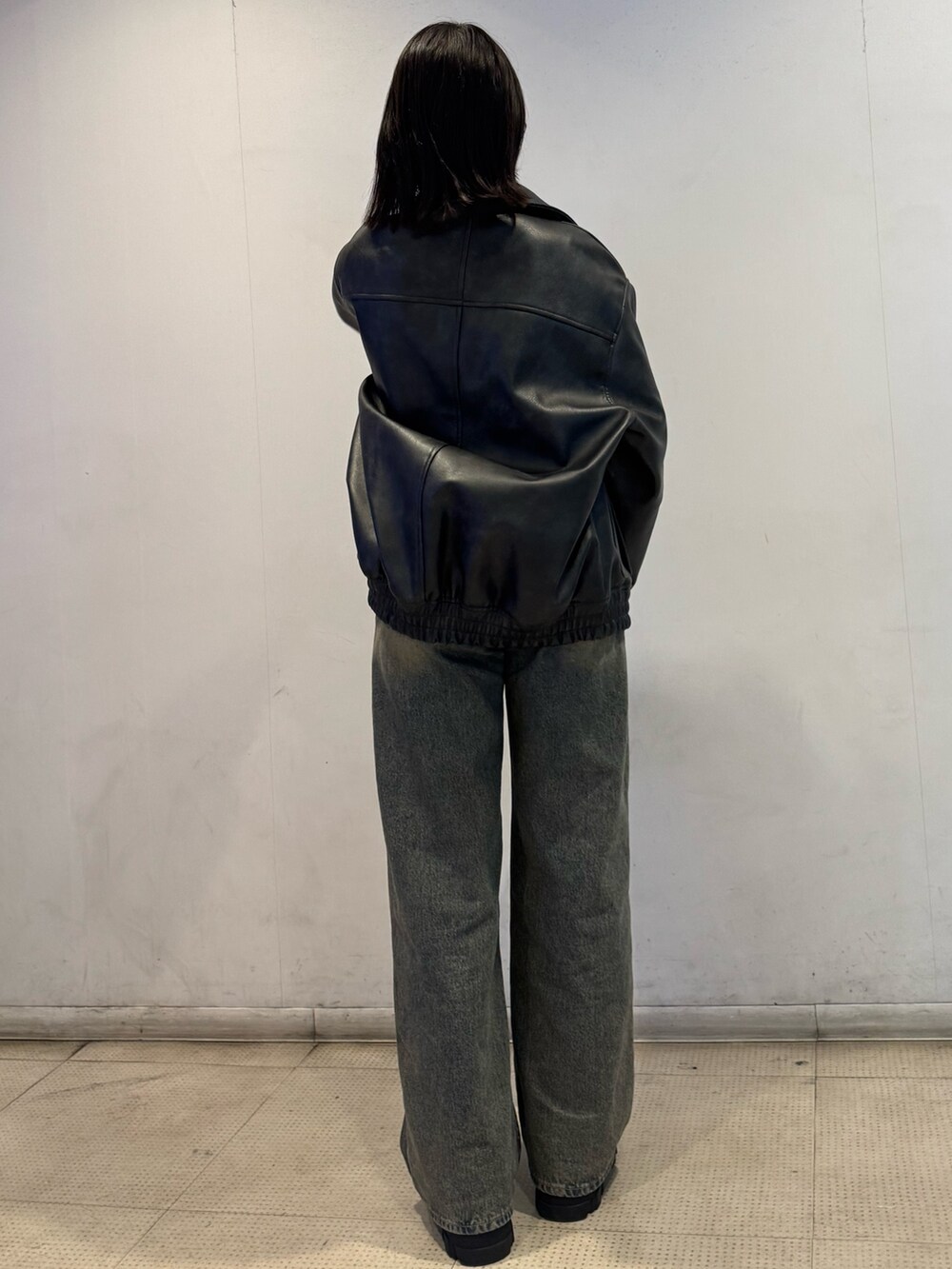 ブラック系のブルゾン、ブラック系のニット/セーター、ブルー系のデニムパンツを着用したレディースの冬コーディネートの3枚目の写真