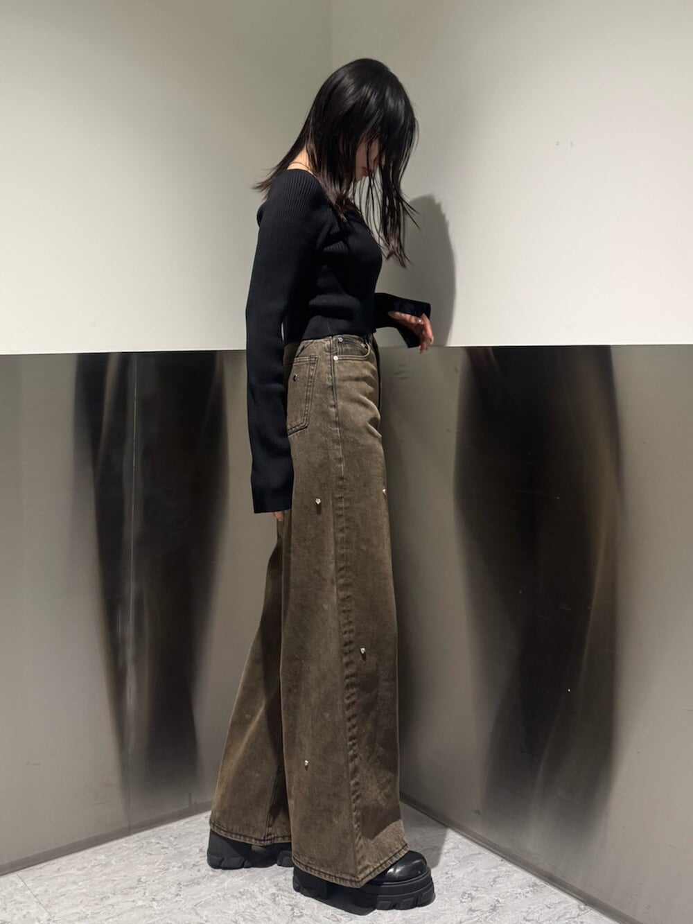 ブラック系のブーツ、ブラック系のニット/セーター、ブラウン系のデニムパンツを着用したレディースの秋コーディネートの2枚目の写真