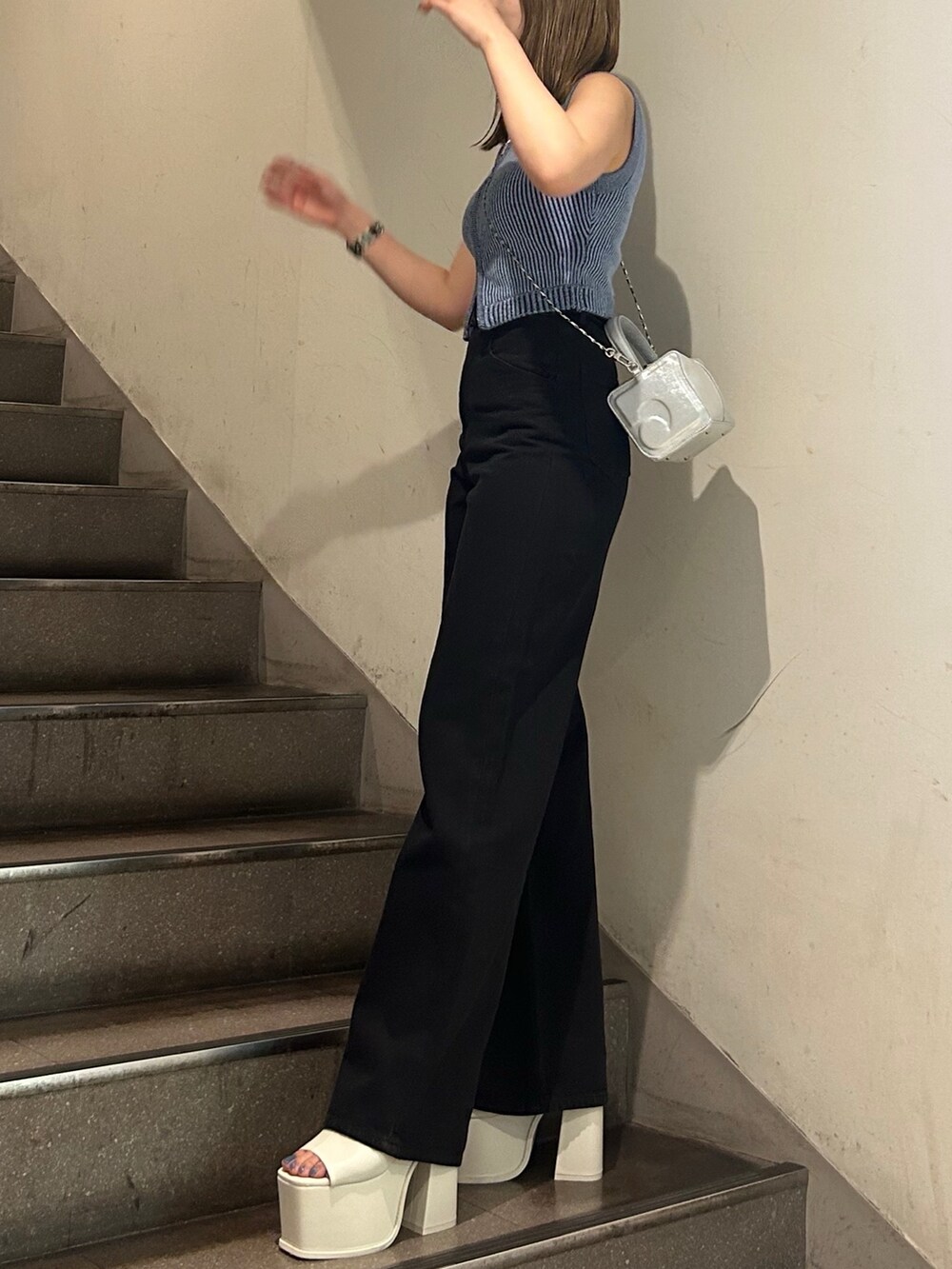 ブルー系のニット/セーター、ブラック系のデニムパンツ、ホワイト系のサンダルを着用したレディースの夏コーディネートの2枚目の写真