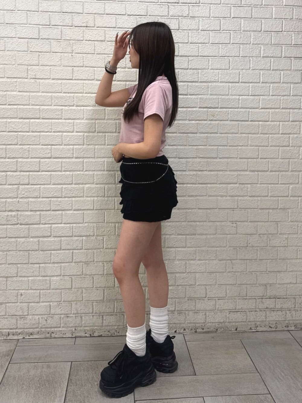 ピンク系のTシャツ/カットソー、ブラック系のスカート、ブラック系のスニーカーを着用したレディースの春コーディネートの2枚目の写真