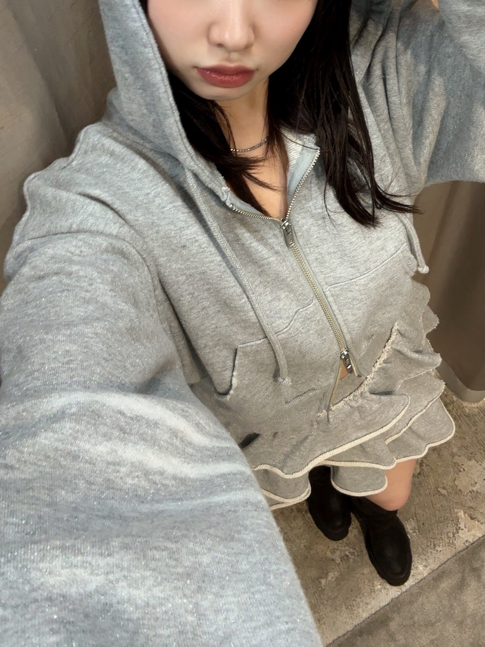 グレー系のパーカー、グレー系のスカート、ブラック系のブーツを着用したレディースの秋コーディネートの5枚目の写真