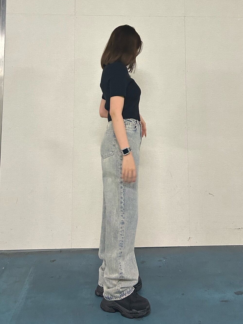 ブラック系のニット/セーター、ブルー系のデニムパンツ、ブラック系のスニーカーを着用したレディースの春コーディネートの4枚目の写真