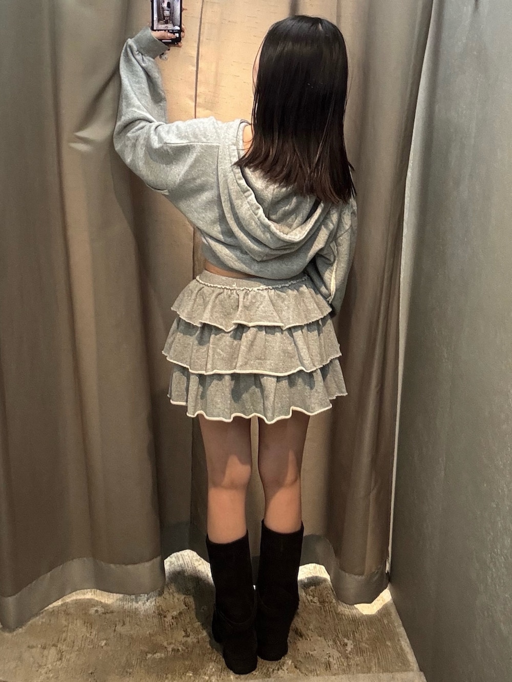 グレー系のパーカー、グレー系のスカート、ブラック系のブーツを着用したレディースの秋コーディネートの4枚目の写真