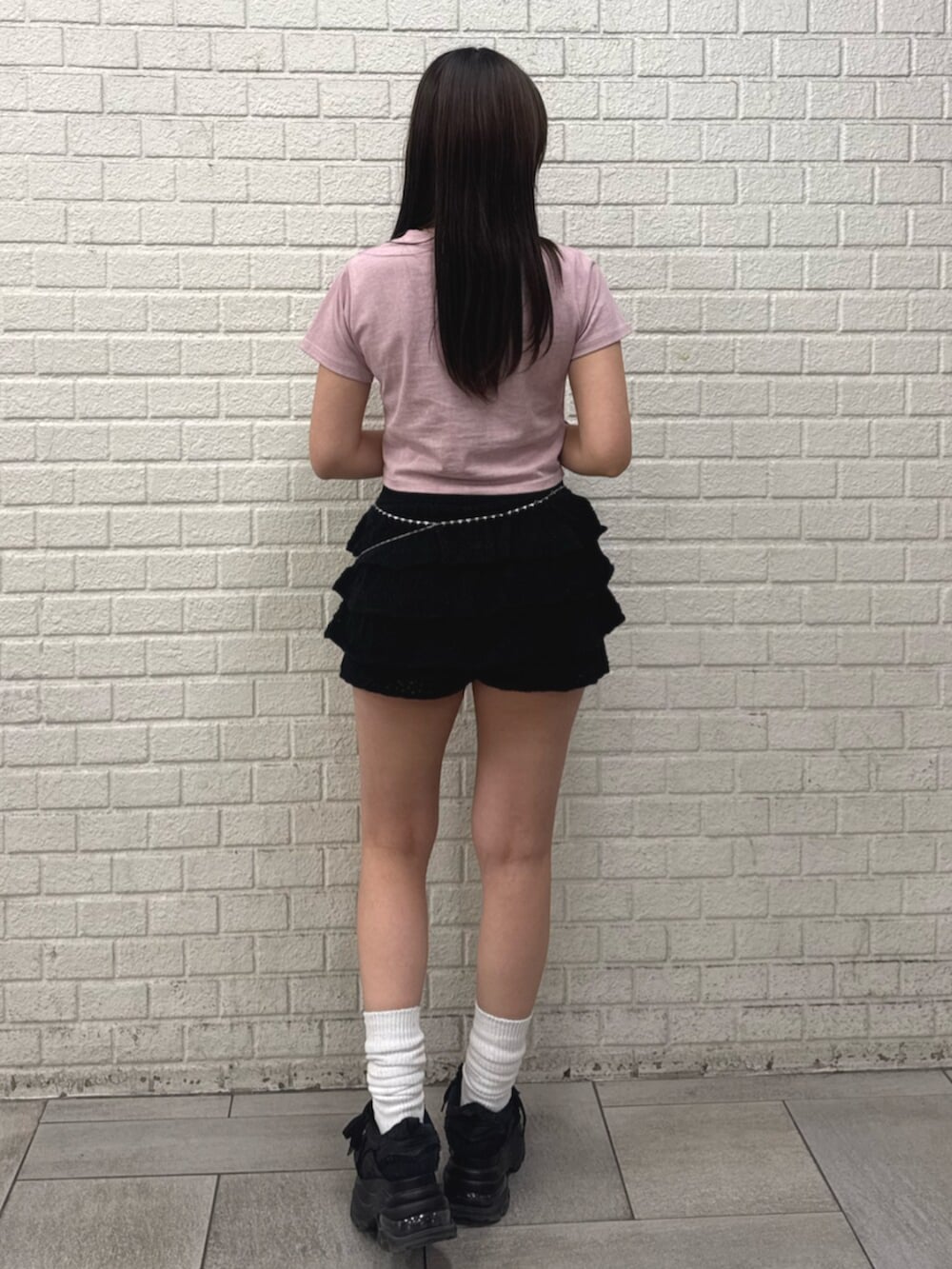 ピンク系のTシャツ/カットソー、ブラック系のスカート、ブラック系のスニーカーを着用したレディースの春コーディネートの3枚目の写真
