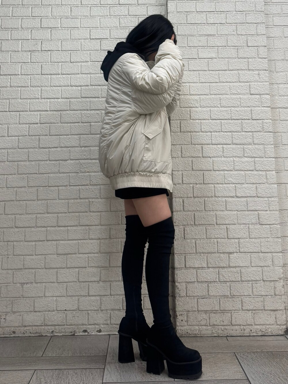 ブラック系のパーカー、ホワイト系のブルゾン、ブラック系のスカートを着用したレディースの秋コーディネートの3枚目の写真