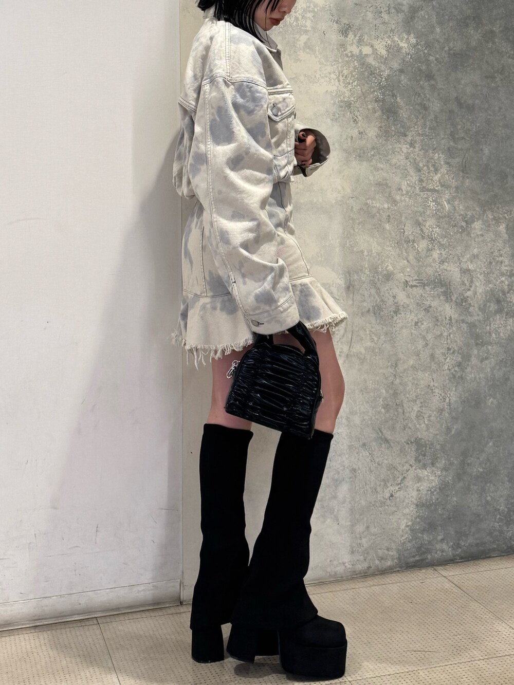 ホワイト系のデニムジャケット、ホワイト系のワンピース、ブラック系のブーツを着用したレディースの冬コーディネートの2枚目の写真