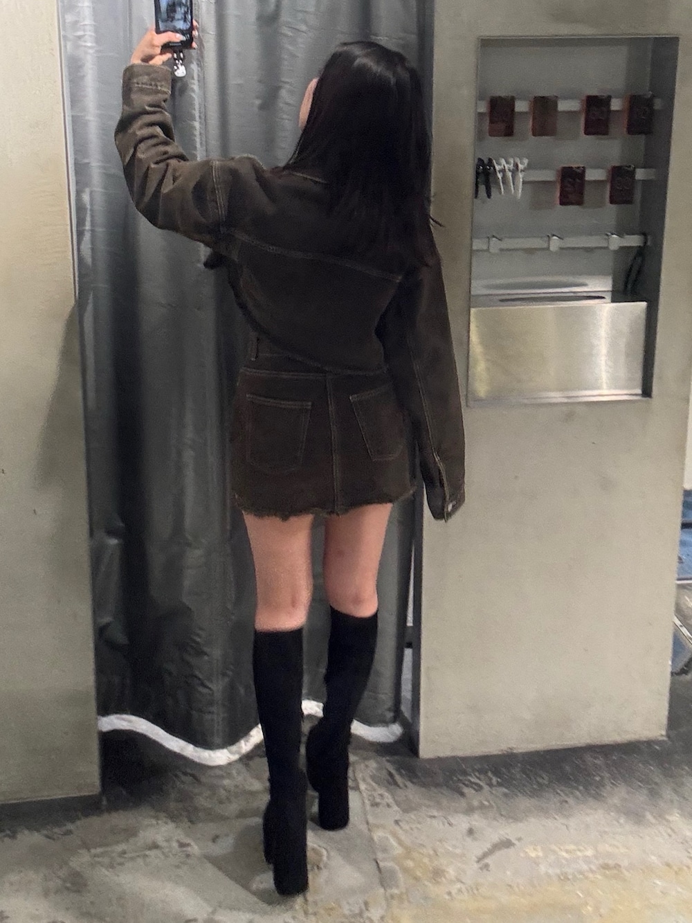 ブラウン系のデニムジャケット、ブラウン系のスカート、ブラック系のブーツを着用したレディースの夏コーディネートの3枚目の写真