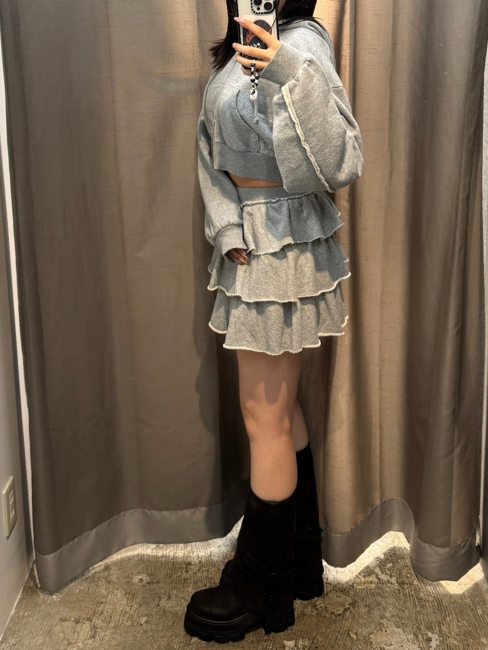 グレー系のパーカー、グレー系のスカート、ブラック系のブーツを着用したレディースの秋コーディネートの3枚目の写真