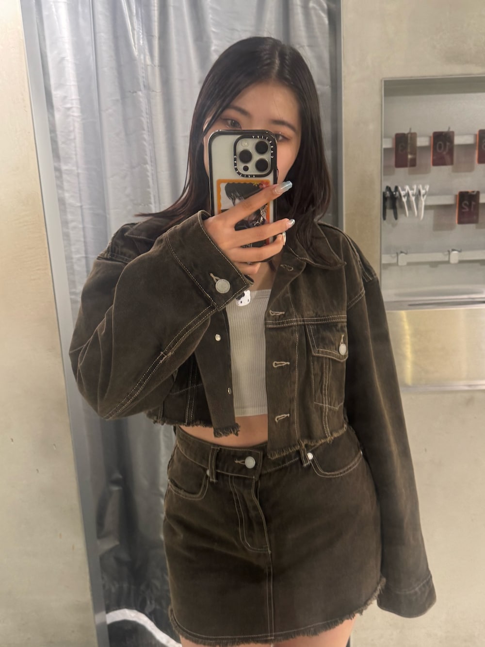 ブラウン系のデニムジャケット、ブラウン系のスカート、ブラック系のブーツを着用したレディースの夏コーディネートの4枚目の写真