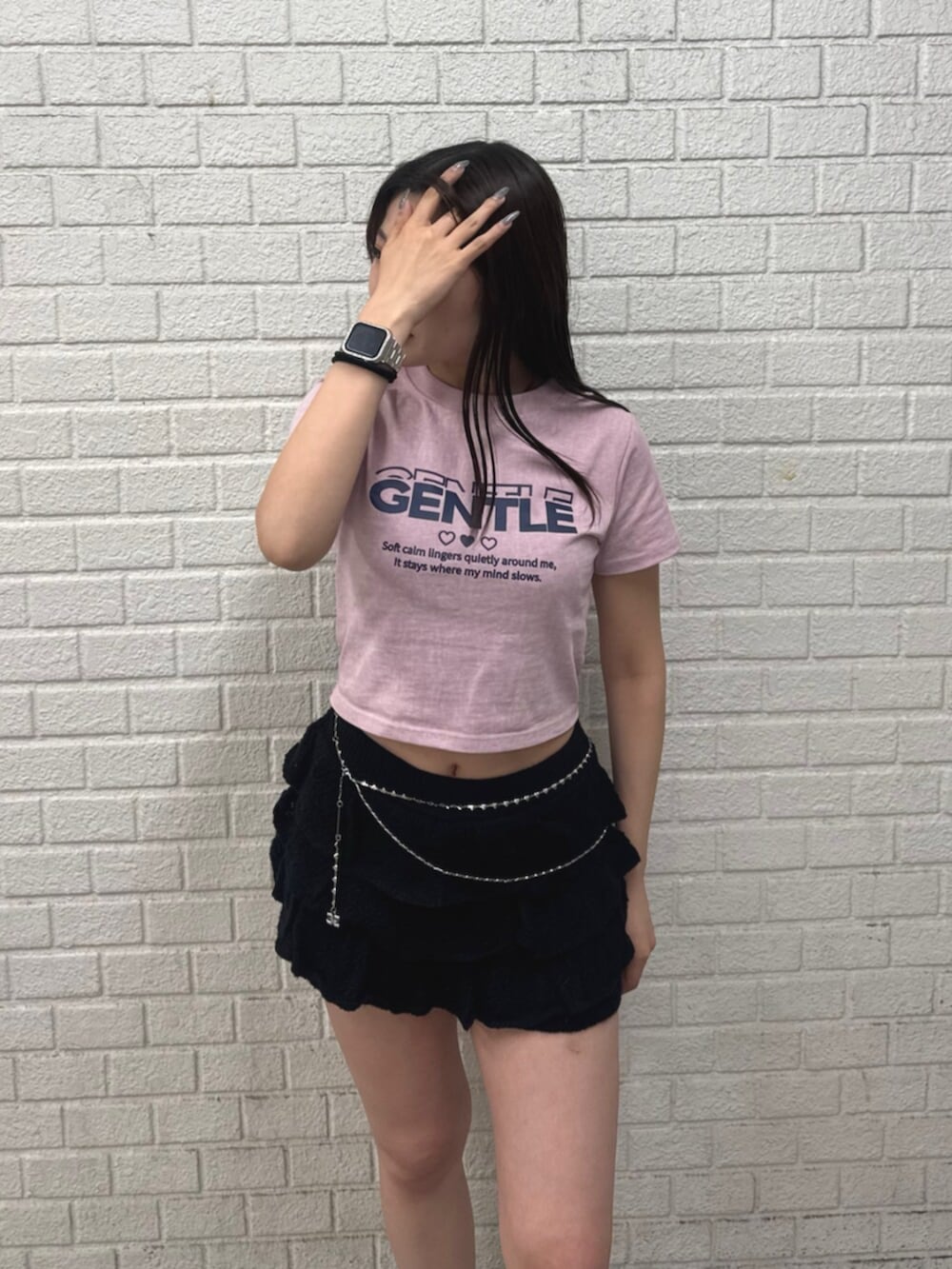 ピンク系のTシャツ/カットソー、ブラック系のスカート、ブラック系のスニーカーを着用したレディースの春コーディネートの4枚目の写真