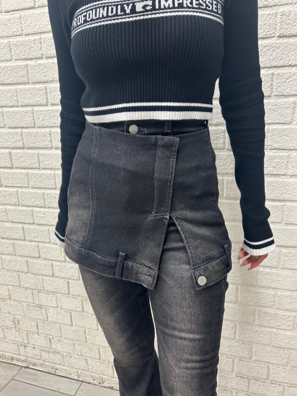 ブラック系のニット/セーター、ブラック系のデニムパンツ、ブラック系のブーツを着用したレディースの秋コーディネートの5枚目の写真