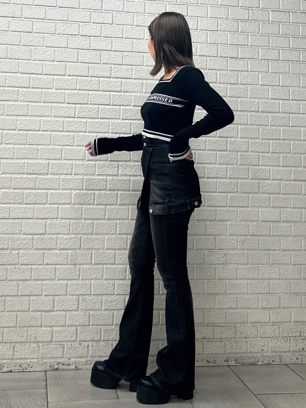 ブラック系のニット/セーター、ブラック系のデニムパンツ、ブラック系のブーツを着用したレディースの秋コーディネートの3枚目の写真