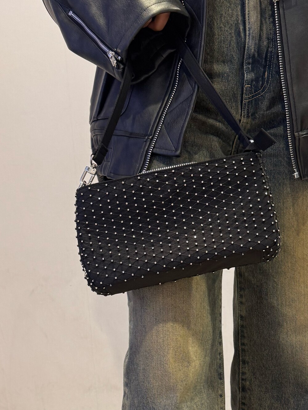 ブラック系のブルゾン、ブラック系のニット/セーター、ブルー系のデニムパンツを着用したレディースの冬コーディネートの5枚目の写真