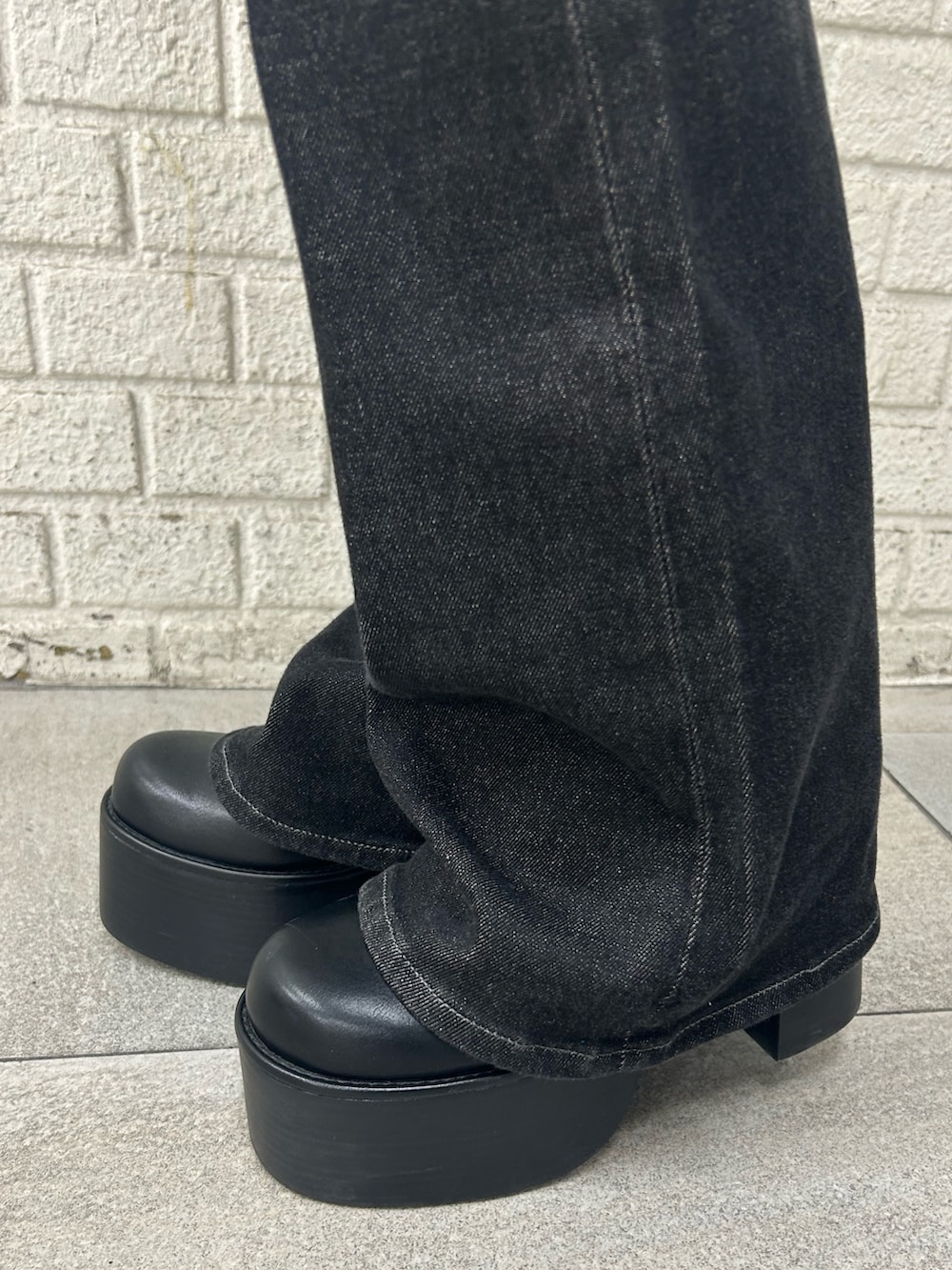 ブラック系のニット/セーター、ブラック系のデニムパンツ、ブラック系のブーツを着用したレディースの秋コーディネートの6枚目の写真