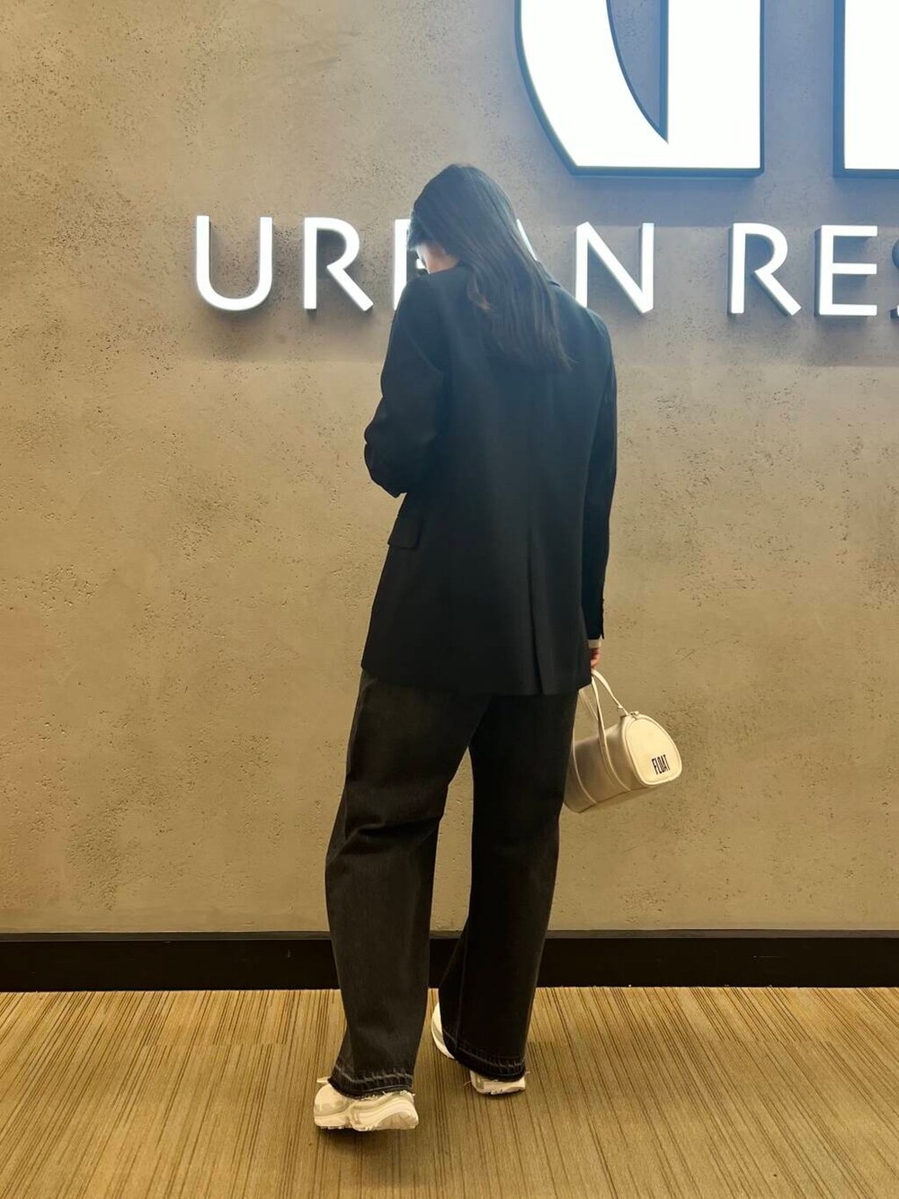 ブラック系のデニムパンツ、ホワイト系のボストンバッグ、ホワイト系のスニーカーを着用したレディースの冬コーディネートの3枚目の写真