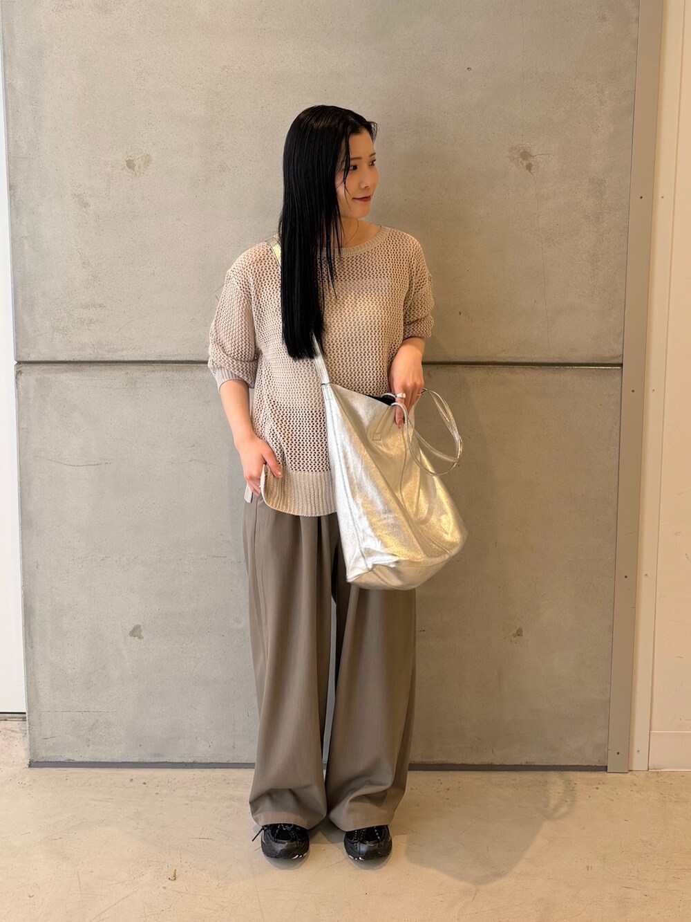 グレー系のニット/セーター、グレー系のその他パンツ、ブラック系のスニーカーを着用したレディースの春コーディネートの2枚目の写真