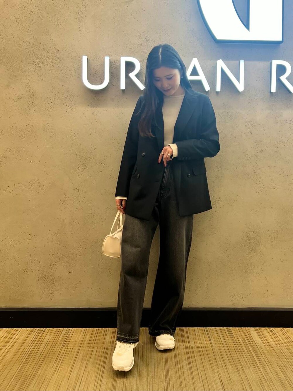 ブラック系のデニムパンツ、ホワイト系のボストンバッグ、ホワイト系のスニーカーを着用したレディースの冬コーディネートの2枚目の写真