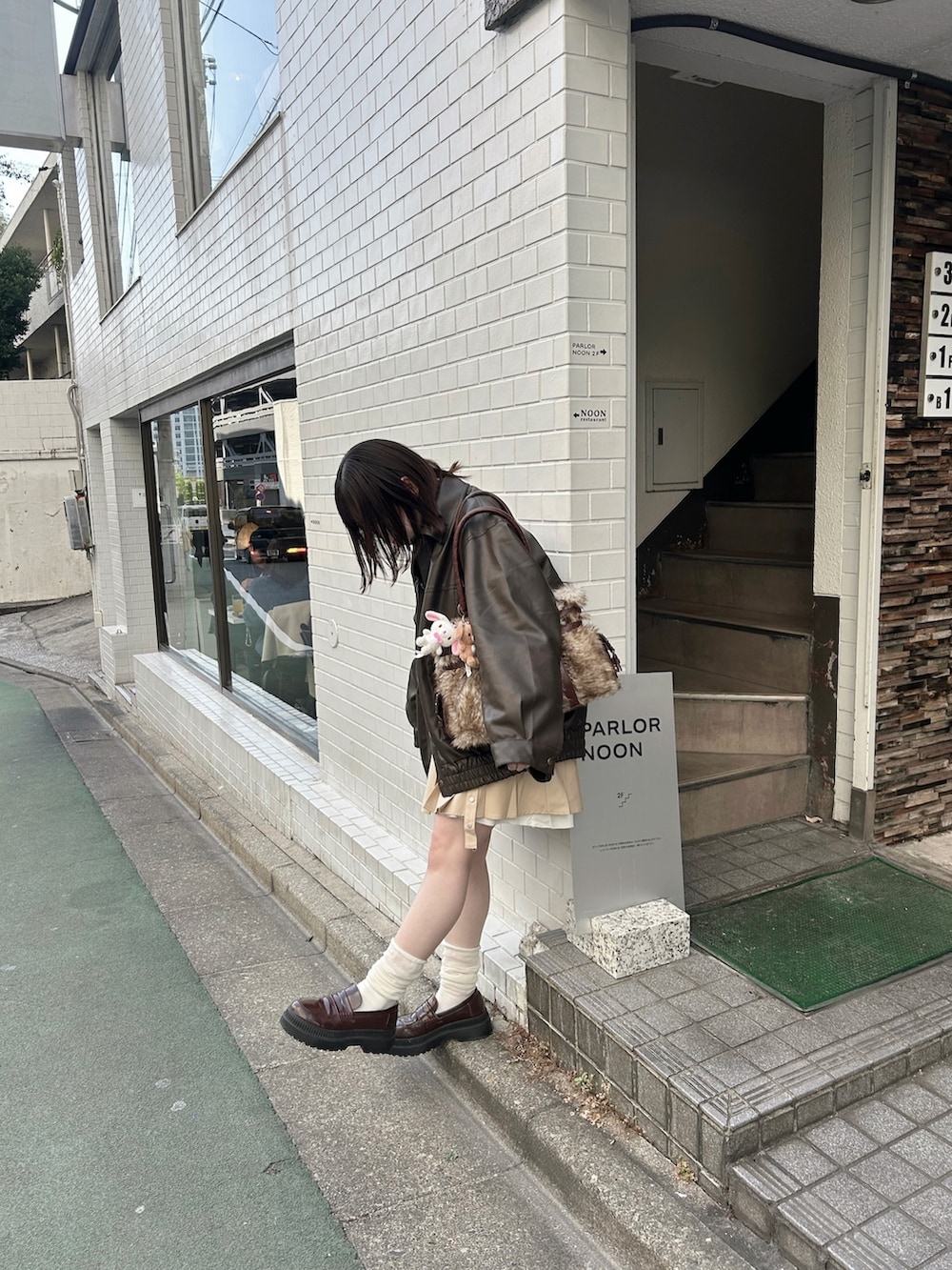 ブルー系のスウェット、ベージュ系のスカート、ブラウン系のブルゾンを着用したレディースの冬コーディネートの3枚目の写真