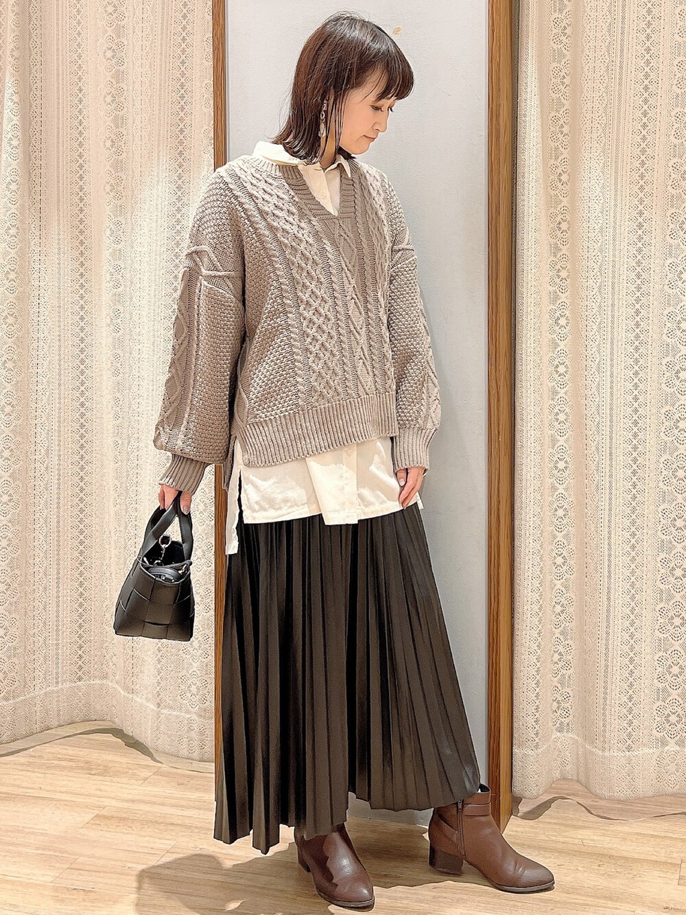 ブラック系のスカート、ブラック系のショルダーバッグ、ベージュ系のニット/セーターを着用したレディースの秋コーディネートの2枚目の写真