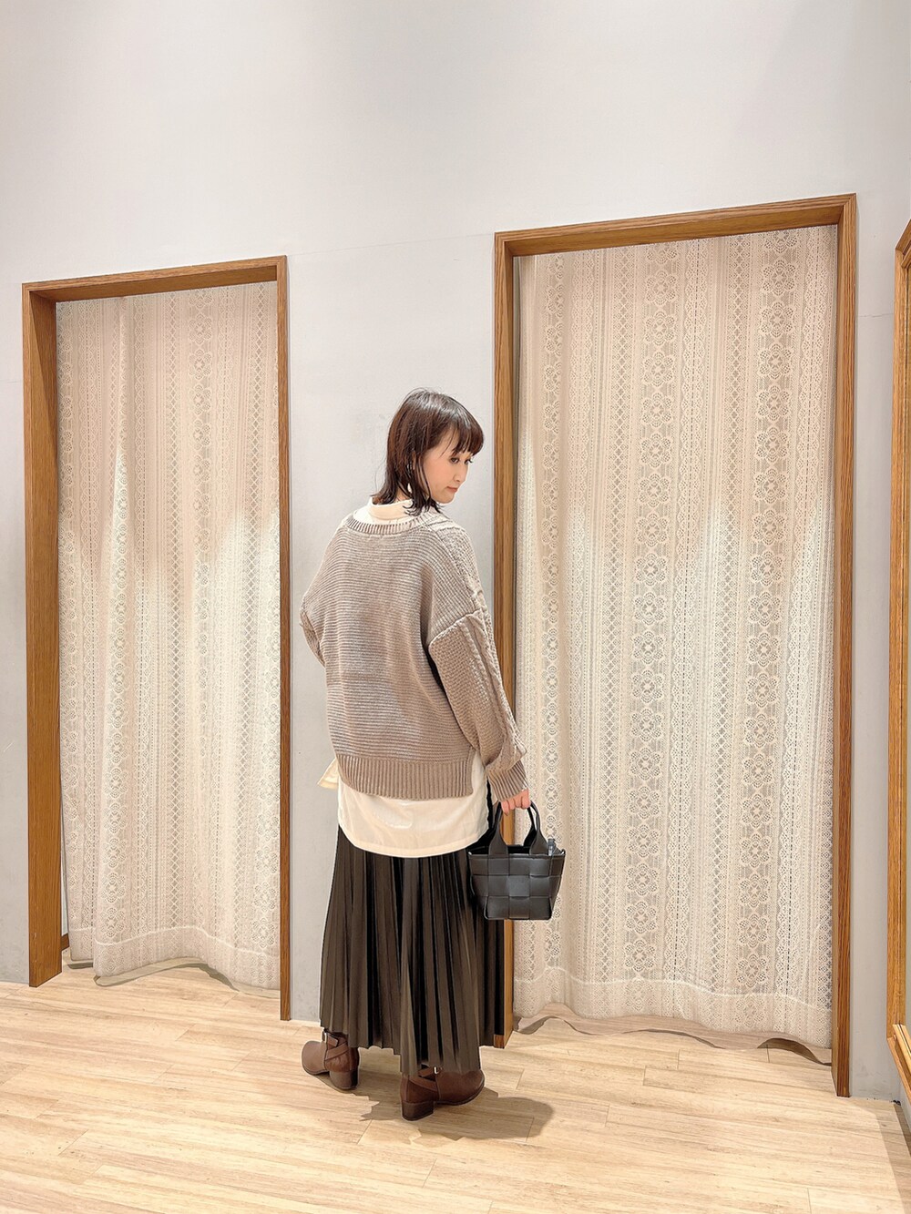 ブラック系のスカート、ブラック系のショルダーバッグ、ベージュ系のニット/セーターを着用したレディースの秋コーディネートの3枚目の写真