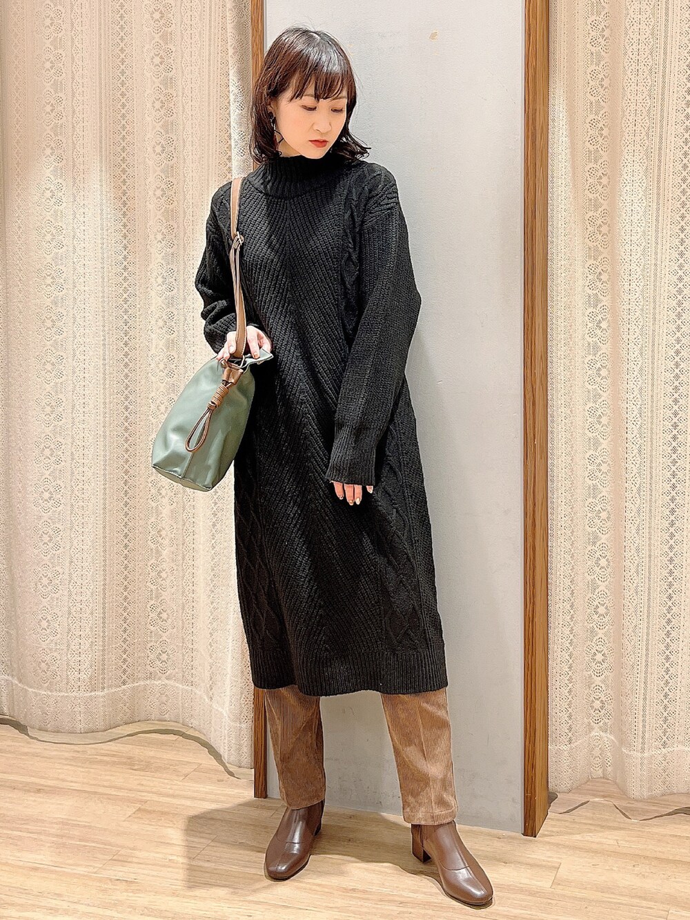 ブラウン系のブーツ、ブラウン系のショルダーバッグ、ブラック系のワンピースを着用したレディースの冬コーディネートの2枚目の写真