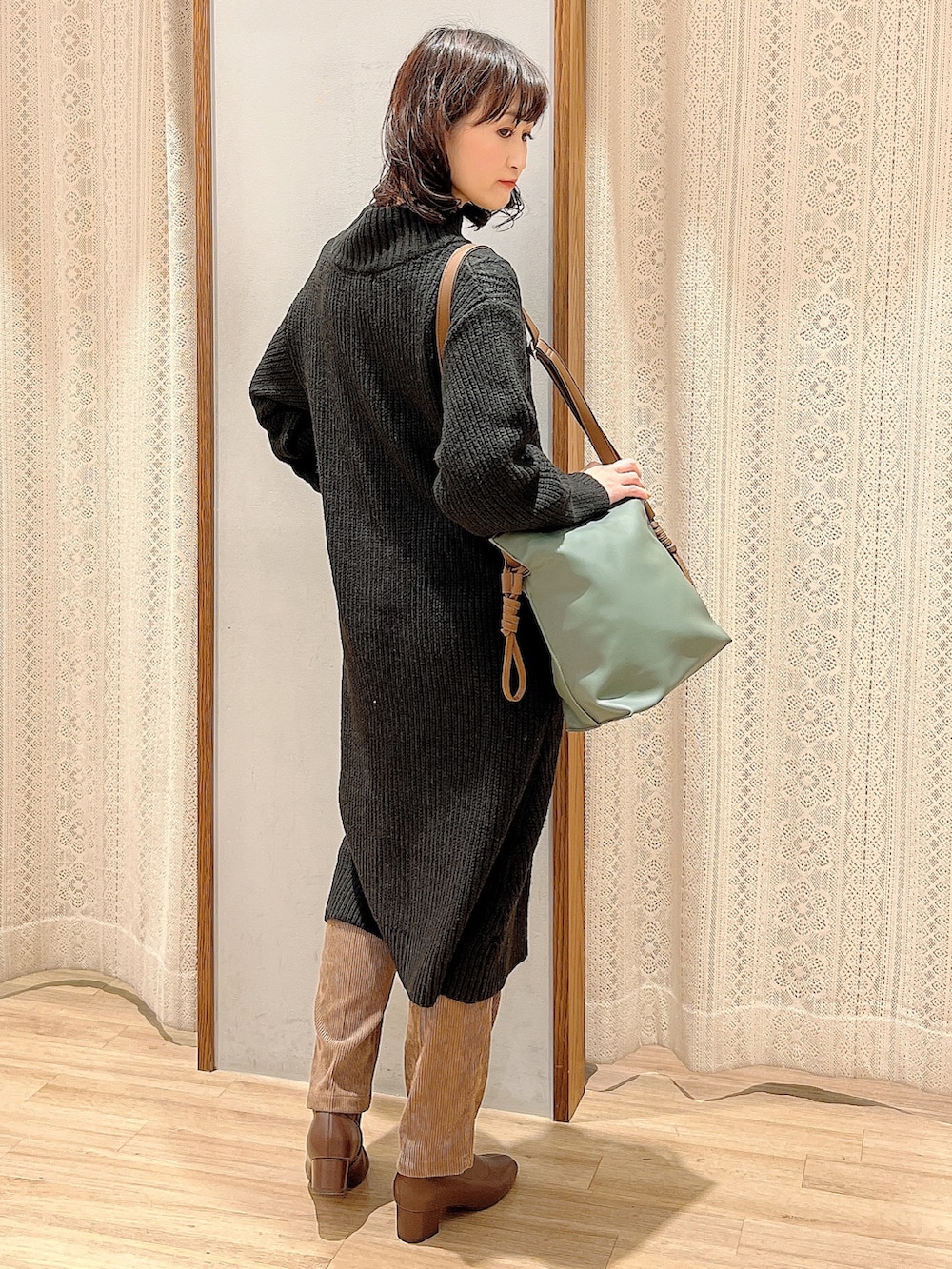 ブラウン系のブーツ、ブラウン系のショルダーバッグ、ブラック系のワンピースを着用したレディースの冬コーディネートの3枚目の写真