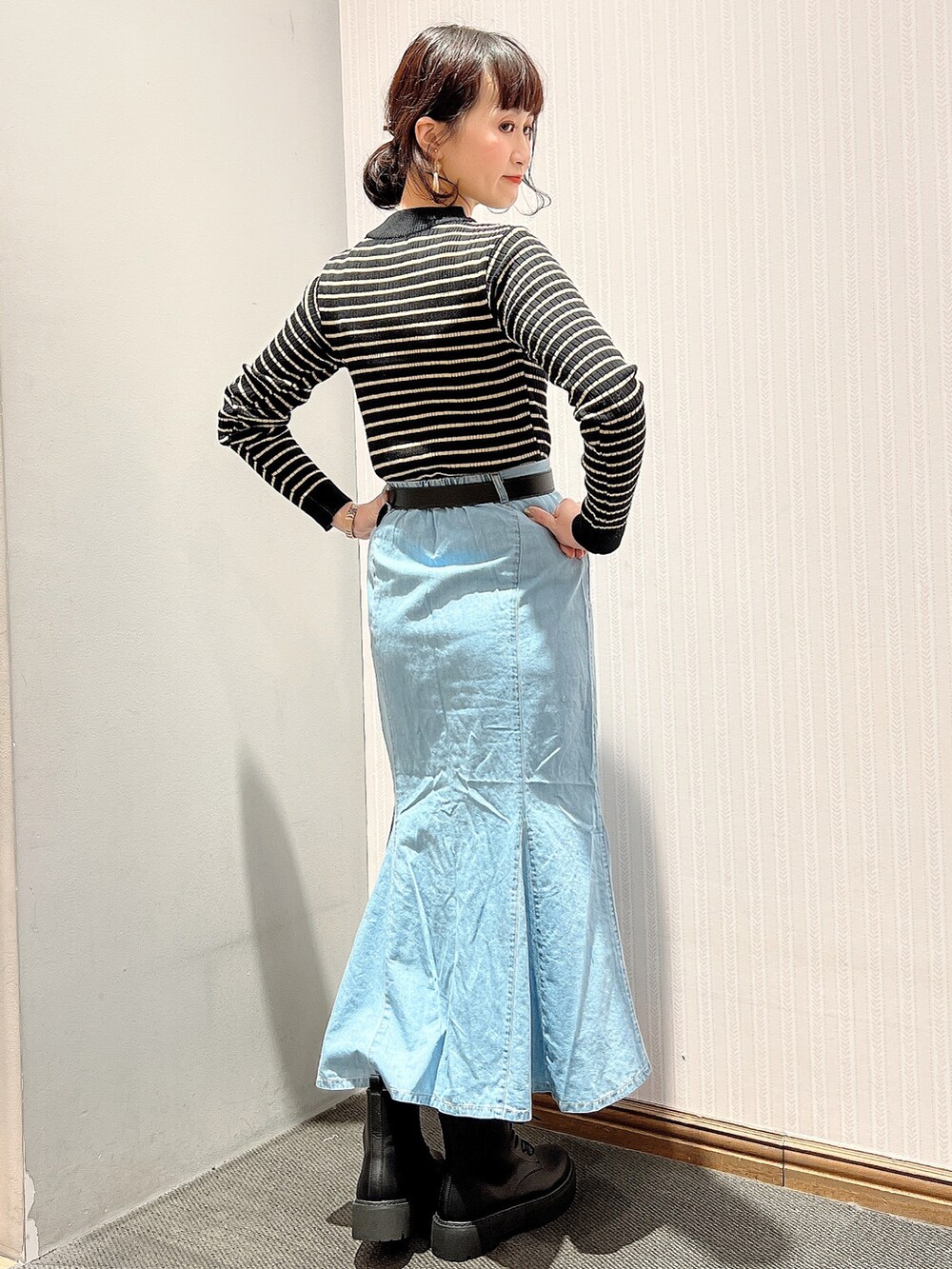 ブラック系のブーツ、ブルー系のデニムスカート、ブラック系のニット/セーターを着用したレディースの冬コーディネートの3枚目の写真