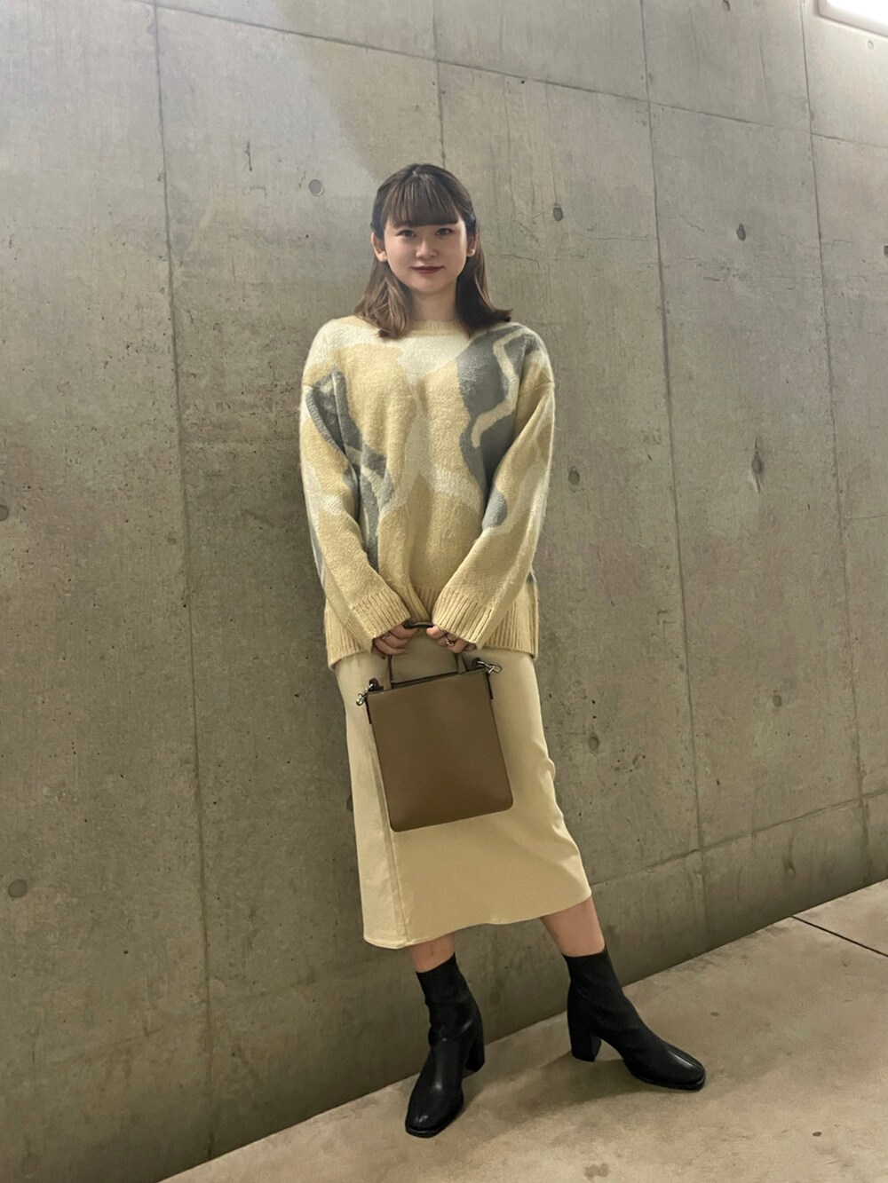 ベージュ系のショルダーバッグ、ベージュ系のニット/セーター、ベージュ系のスカートを着用したレディースの秋コーディネートの2枚目の写真