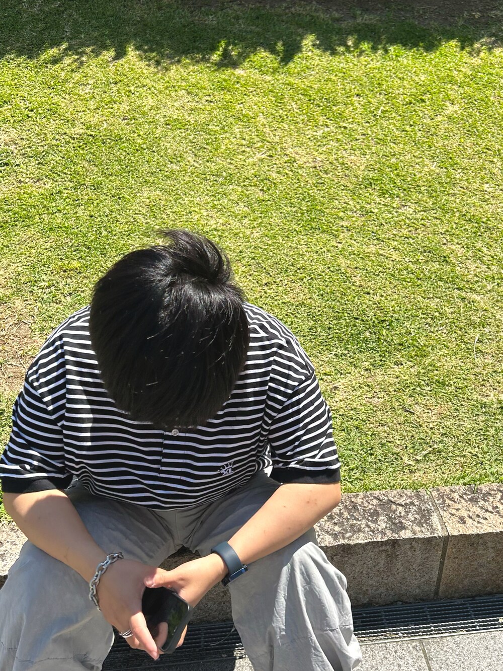 ブラック系のポロシャツ、グレー系のカーゴパンツ、ホワイト系のスニーカーを着用したレディースの夏コーディネートの2枚目の写真