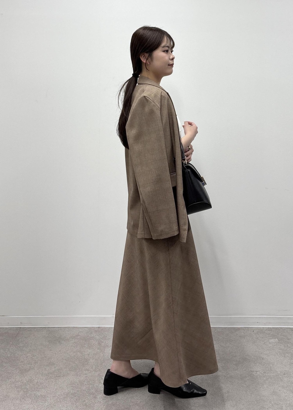 ブラウン系のスカート、ホワイト系のカーディガン/ボレロ、ブラウン系のテーラードジャケットを着用したレディースの春コーディネートの2枚目の写真