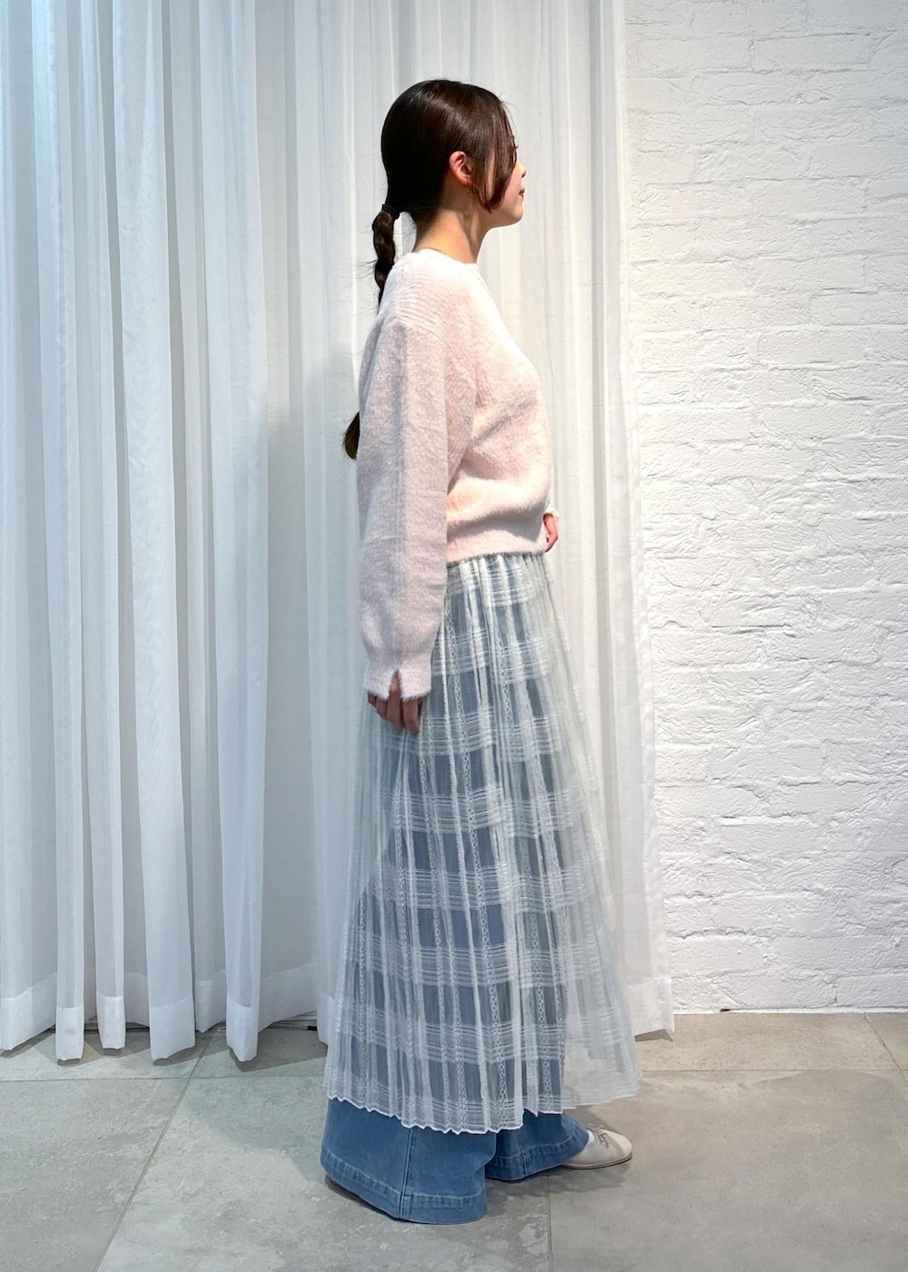 ブルー系のデニムパンツ、ピンク系のニット/セーター、ホワイト系のスカートを着用したレディースの冬コーディネートの2枚目の写真